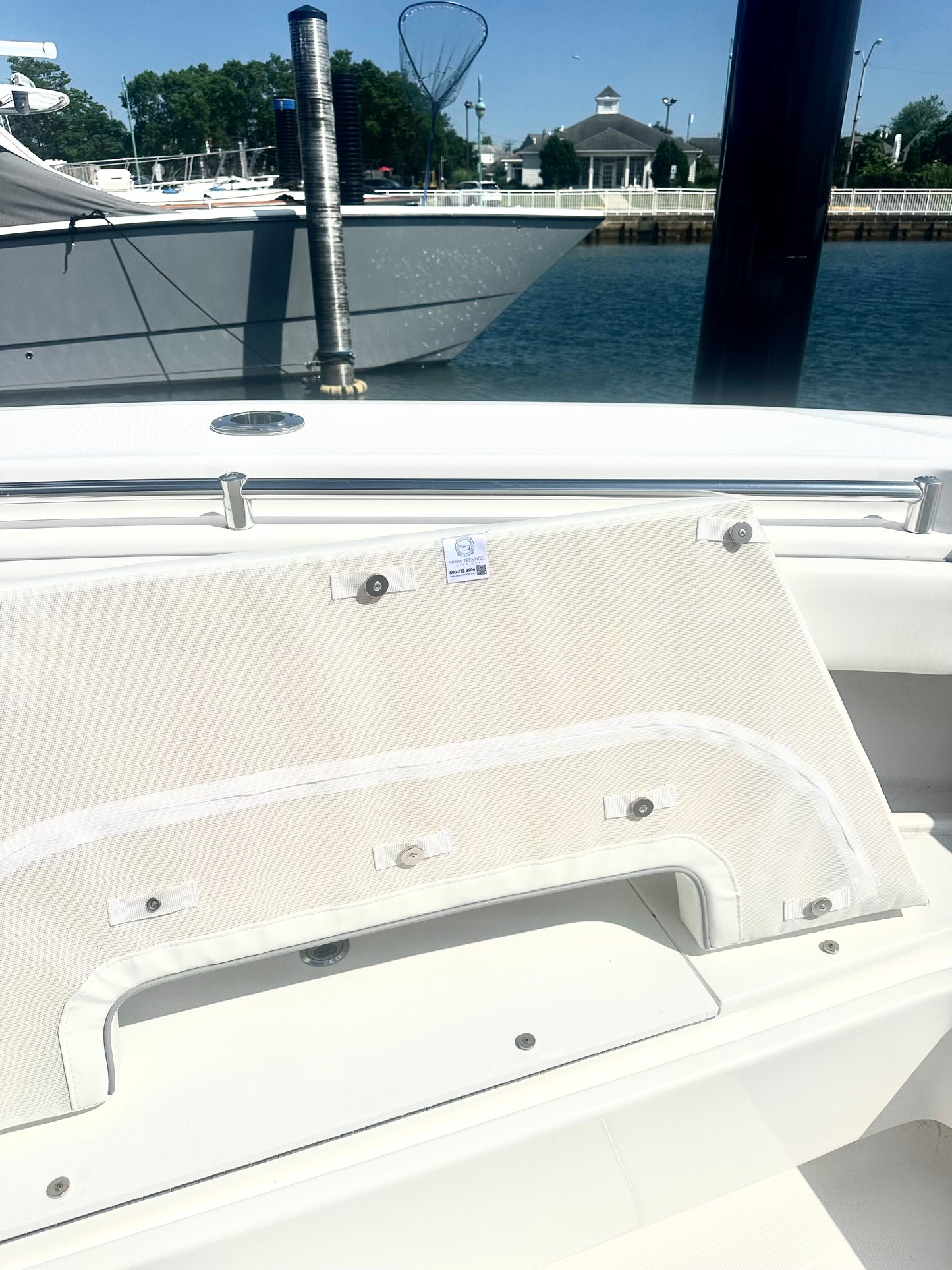 Close-up of a boat's white interior with metal fixtures, water and dock in the background.
