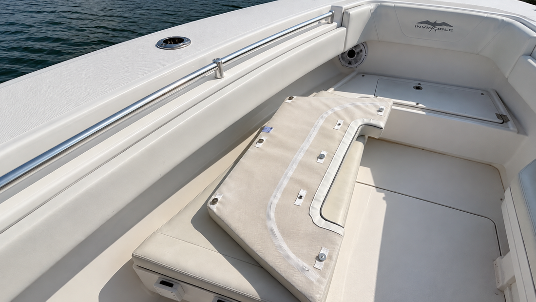 A boat deck with white cushioned bench seating and an Invincible brand logo on the interior hull.